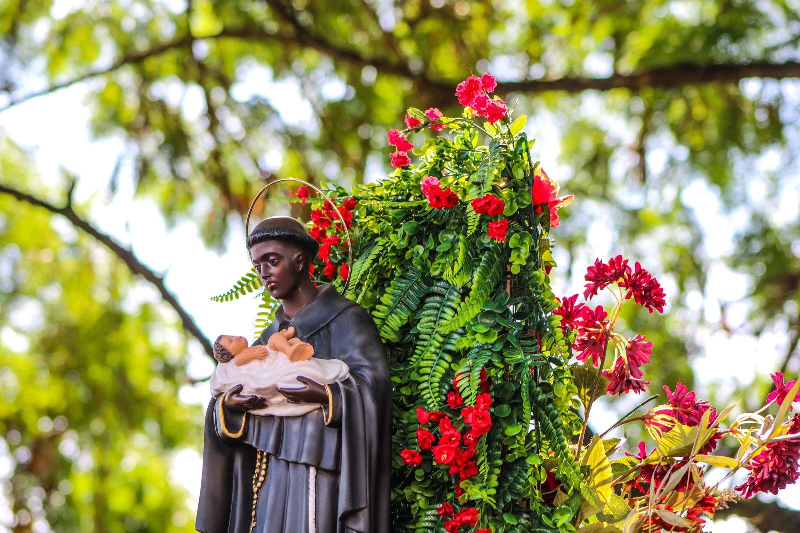 A imagem de São Benedito, enfeitada com flores vermelhas e folhagens